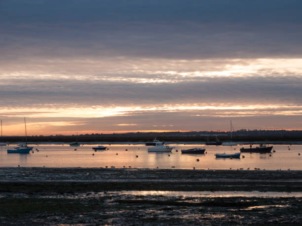 istock sun set sky dramatic clouds sea front beach harbor marina boats moored landscape 877184084