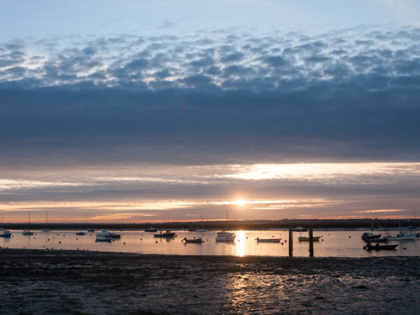 istock sun set sky dramatic clouds sea front beach harbor marina boats moored landscape 877184088