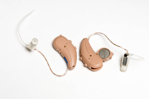 крупным планом пара крошечных современных слуховых аппаратов на белом фоне - hearing aid isolated technology healthcare and medicine стоковые фото и изображения