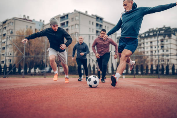 Goal is the target Four people playing football in schoolyard schoolyard fight stock pictures, royalty-free photos & images