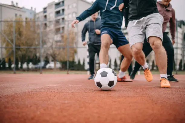 Four people playing football in schoolyard