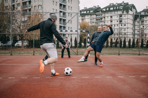 Sunday is day for soccer Four people playing football in schoolyard schoolyard fight stock pictures, royalty-free photos & images