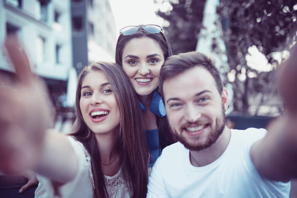 istock Young Smiling Friends Taking a Selfie in Coffee Shop 877202000