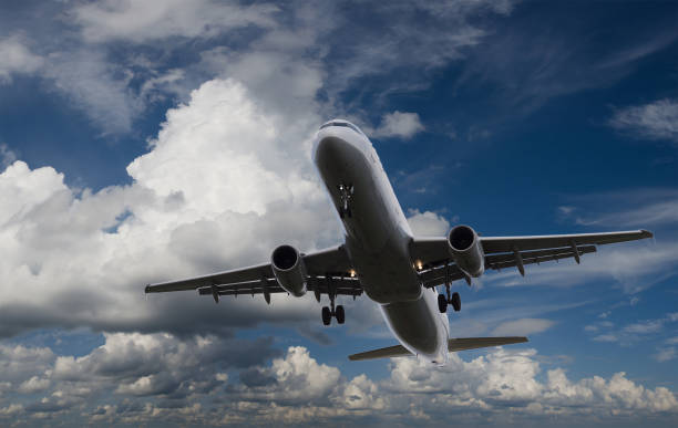 istock Airplane flying in sky with l clouds 877208444
