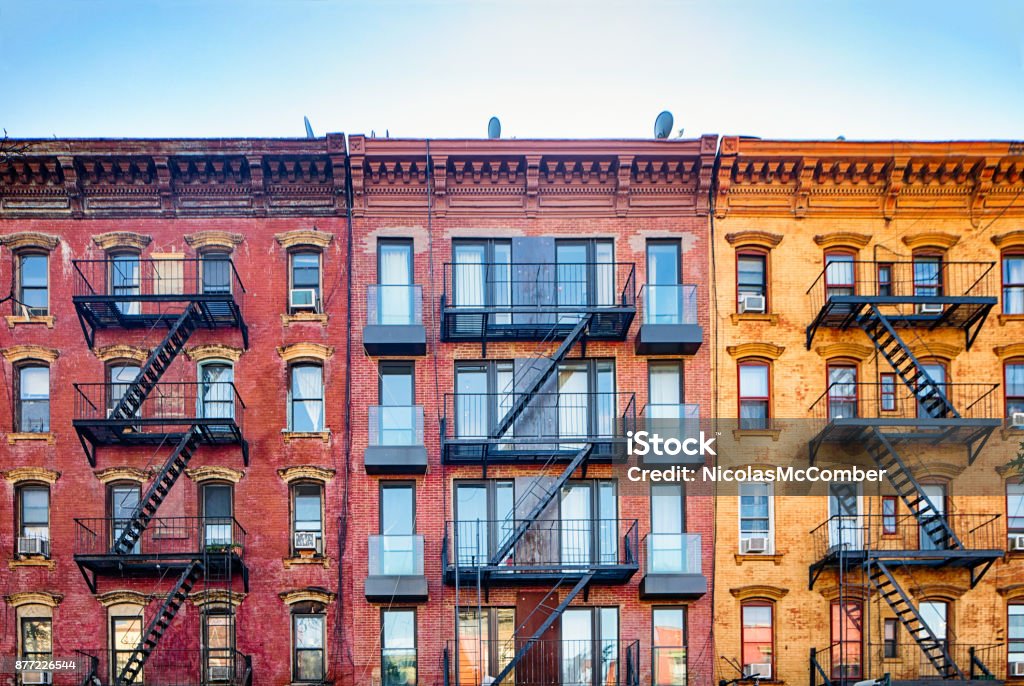Top stories of colorful Williamsburg apartment buildings with steel fire escape stairways Top stories of colorful Williamsburg brownstone apartment buildings with steel fire escape stairways. Copy space in the sky above. New York City Stock Photo