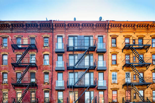 Top stories of colorful Williamsburg apartment buildings with steel fire escape stairways Top stories of colorful Williamsburg brownstone apartment buildings with steel fire escape stairways. Copy space in the sky above. flat stock pictures, royalty-free photos & images