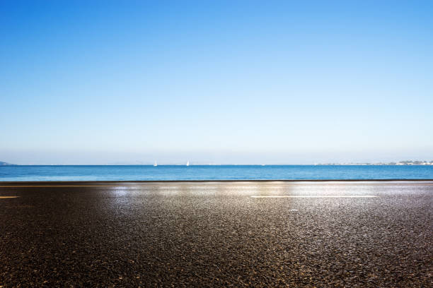istock empty asphalt road with blue sea in blue sky 877236078
