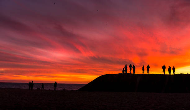 istock Silhouette of group of people watching sun setting on horizon 877253162
