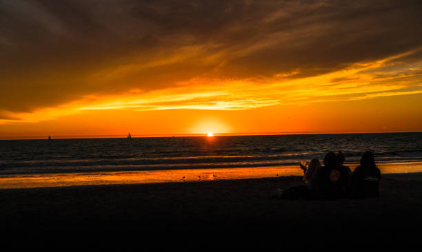 istock Silhouette of group of people watching sun setting on horizon 877253670