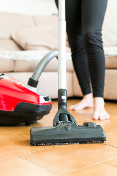 istock Young woman using a vacuum cleaner in the house. 877254026