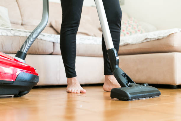 istock Young woman using a vacuum cleaner in the house. 877254146