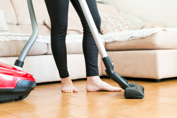 istock Young woman using a vacuum cleaner in the house. 877254276