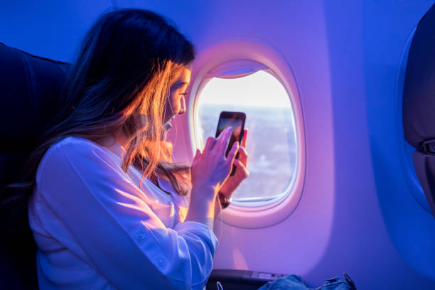 istock Young woman enjoys sunset from airplane window 877254326