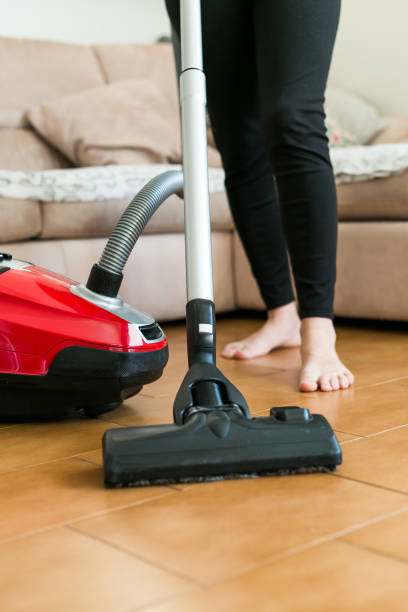 istock Young woman using a vacuum cleaner in the house. 877254428