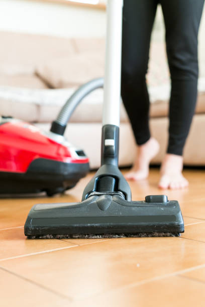 istock Young woman using a vacuum cleaner in the house. 877254490
