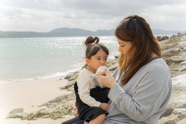 istock Mother and girl playing on the beach 877254632