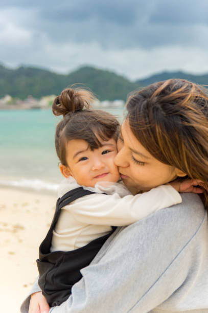 istock Mother and girl playing on the beach 877254832