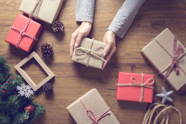 istock Hand holding Christmas gift box and tree branch decor on wooden table background. 877264014