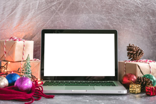 istock Laptop with white screen, gift boxes and christmas decoration on the table. 877267212