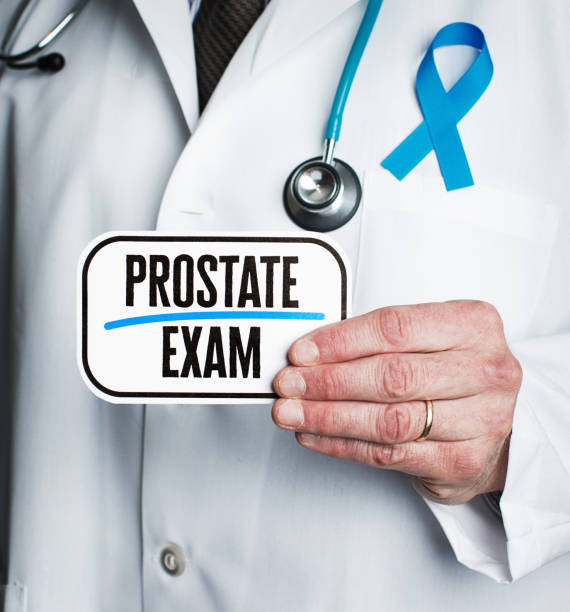 istock Doctor with stethoscope in white lab coat holding sign reading prostate exam 877277236