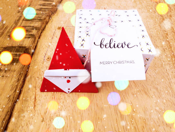 istock Christmas decoration on a wooden table with square gift box for celebration with snow falling and colorful bokeh best Christmas holidays background image for invitation and banner 877281108