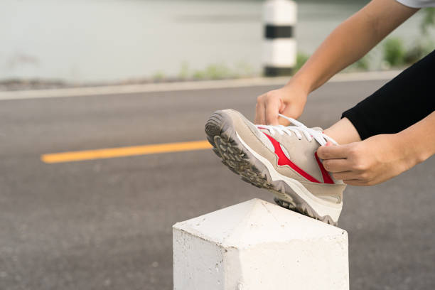 istock Woman tying shoelace his before starting running 877290180