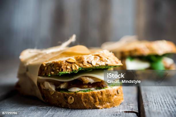 Panino Con Pane Ai Cereali Pollo Pesto E Formaggio Sullo Sfondo Rustico In Legno - Fotografie stock e altre immagini di Panino ripieno