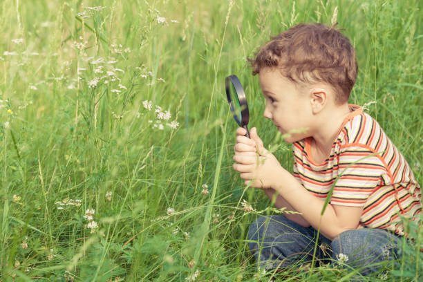istock Happy little boy exploring nature with magnifying glass 877294540