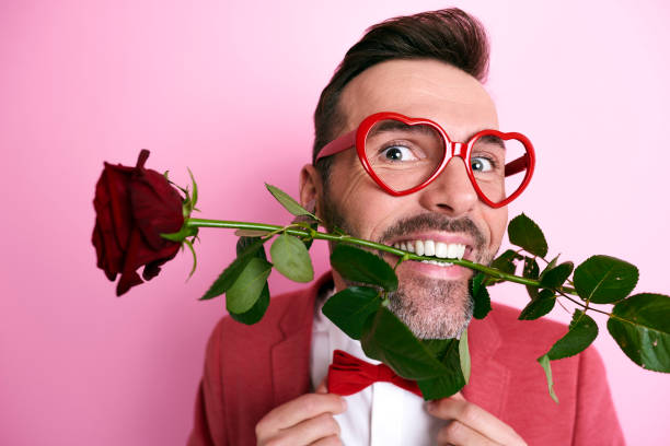 uomo che tiene una rosa in bocca - flirting humor valentines day love foto e immagini stock