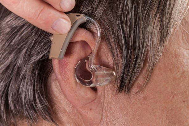 istock Closeup senior woman using hearing aid 877304230