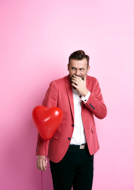 istock Man with heart shape balloon giggling 877304788