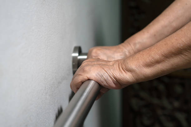 istock Elderly woman holding on handrail for support walking 877304994