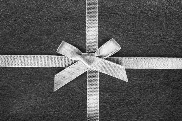 White tied silk ribbon on black wrapping paper as a background
