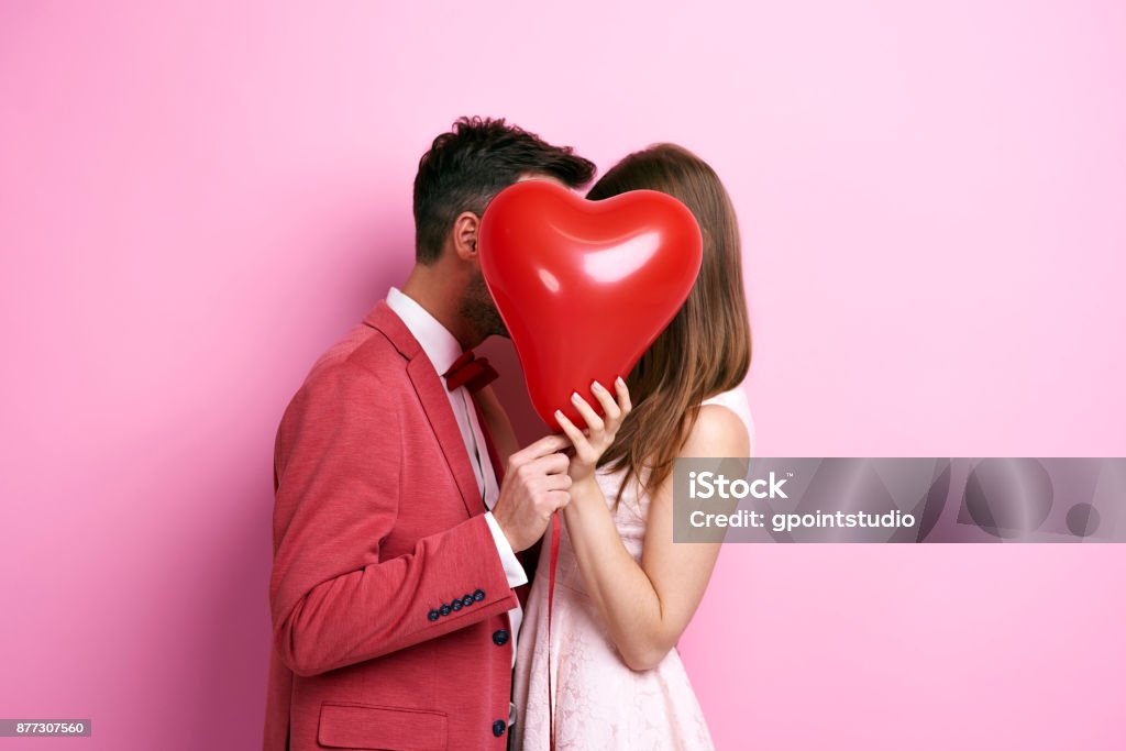 Casal afetuoso, cobrindo o rosto com balão e beijando - Foto de stock de Dia dos Namorados royalty-free