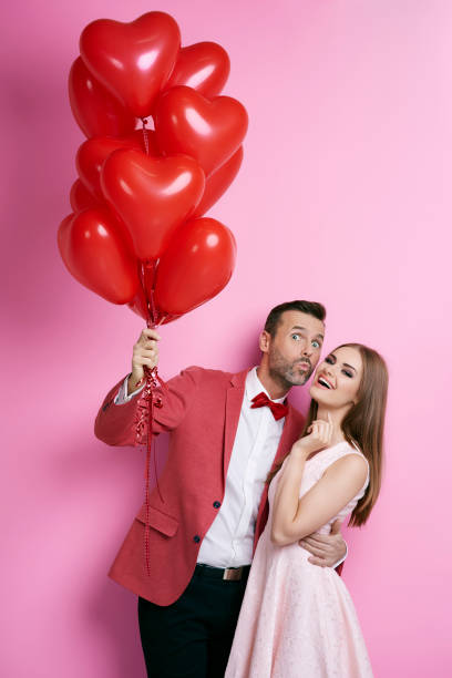 istock Affectionate couple with heart shape balloons flirting 877309420