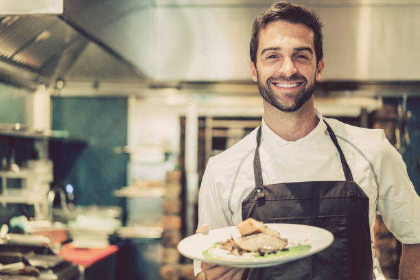 istock Smiling male chef holding prepared dish in kitchen 877309724