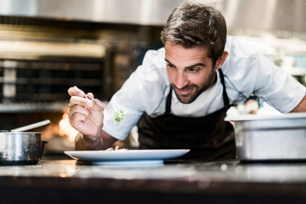 chef hombres guarnición de alimentos en cocina - chef fotografías e imágenes de stock