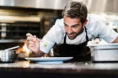 Male chef garnishing food in kitchen