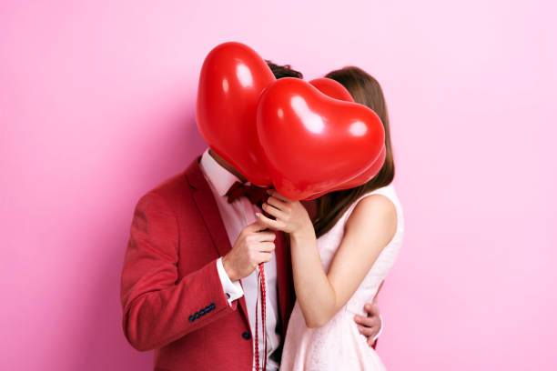 пара целоваться за воздушными шарами - love valentines day heart shape kissing стоковые фото и изображения