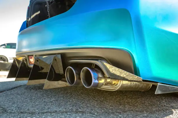 Dual exhaust pipes on a custom car with rear spikes and teal paint. Custom cars in Southern California summer 2017