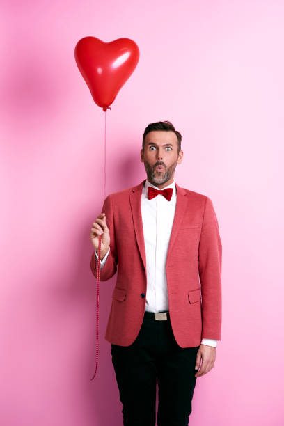 Surprised man holding heart shape balloon