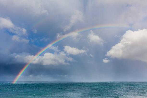 Beautiful double rainbow over ocean water with storm clouds in the sky closeup stock photo