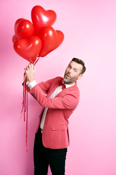 istock Surprised man holding heart shape balloons 877320576