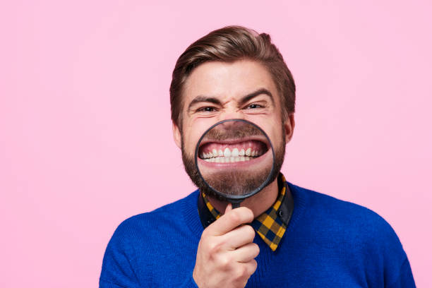 homem que segura a lupa contra boca aberta - clenching teeth - fotografias e filmes do acervo