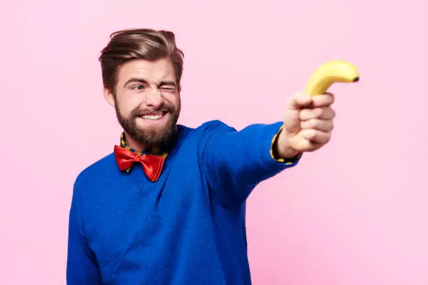 Photo of Man holding banana as a gun