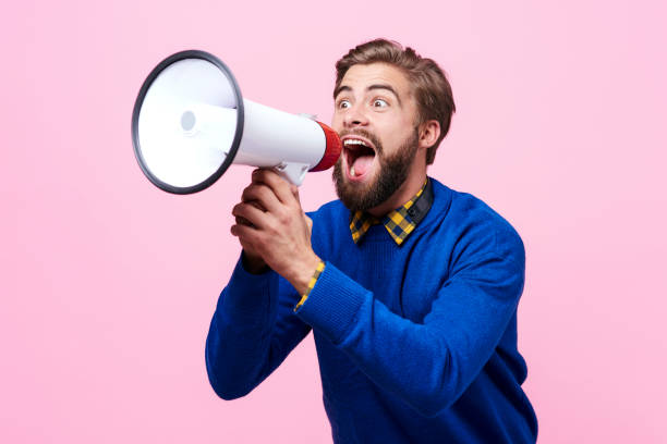 Man yelling into a megaphone Man yelling into a megaphone assertiveness stock pictures, royalty-free photos & images