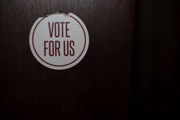 istock Peeling round sticker with the words Vote For US printed 877329716