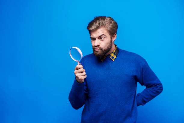 surprised man looking through a magnifying glass - olhando através imagens e fotografias de stock