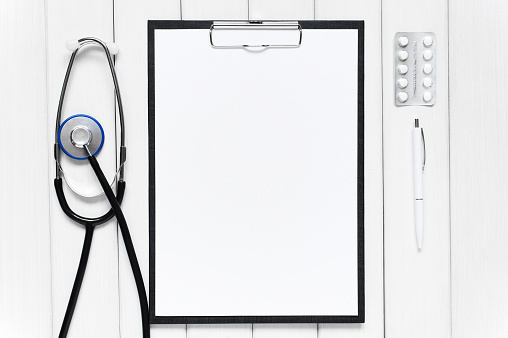 White background with medical tools. Empty sheet of white paper centered.