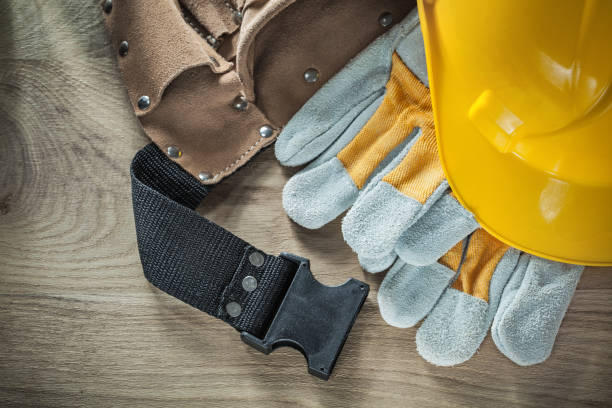 istock Leather construction belt safety gloves building helmet on woode 877349068